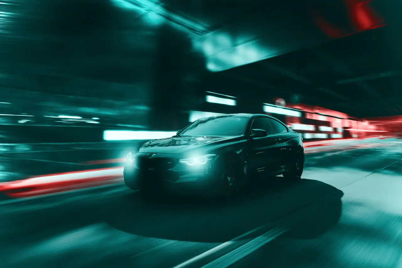 Black performance coupe moving through city lights at night